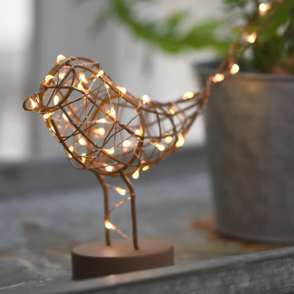 Decorative light fixture shaped like a bird with string lights on a blurred indoor background