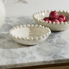 Two small ceramic bowls with fruit on a marble surface