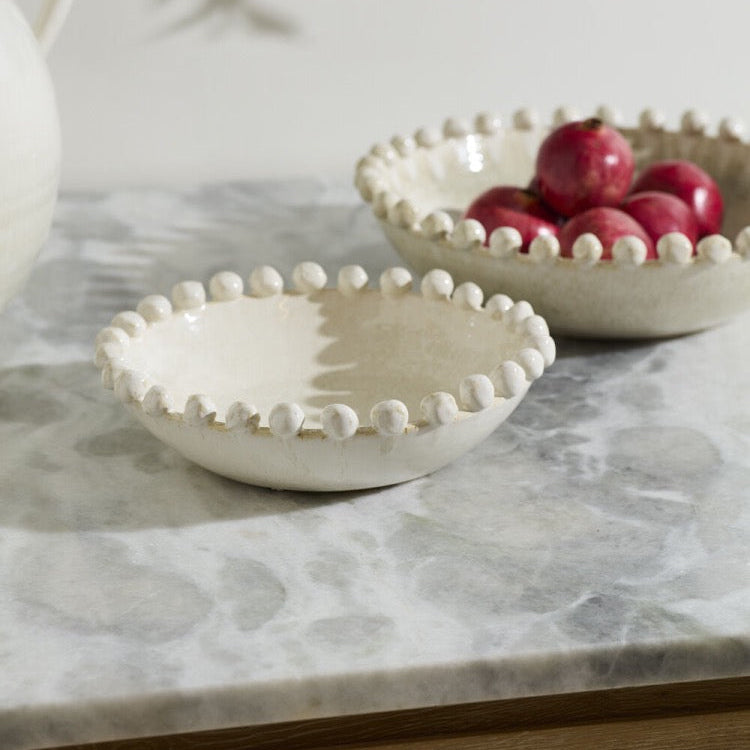 Two small ceramic bowls with fruit on a marble surface