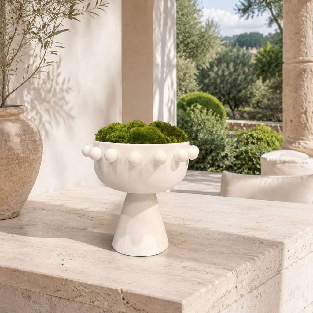 White pedestal planter bowl with ball trim detail, styled on a stone ledge with moss and greenery