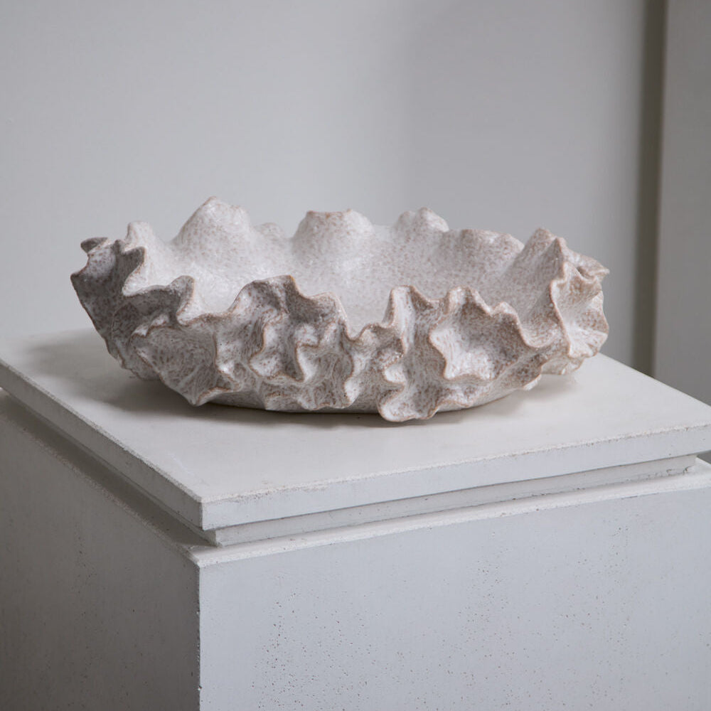Textured ceramic bowl on a white pedestal against a plain background