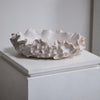 Textured ceramic bowl on a white pedestal against a plain background